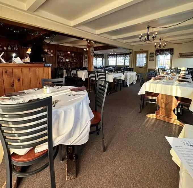 The dining room: white tablecloths, wood-paneled bar and chandeliers